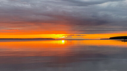 Sunset ignites fiery skies over tranquil waters, evoking Lohri's warmth and Samhain's introspective...