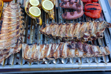 Delicious bbq ribs grilling on a barbecue with sausages, chicken and vegetables