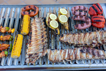 Delicious spare ribs, sausages, chicken, peppers and corn grilling on barbecue