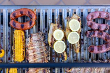 Assorted meat, chicken and vegetables cooking on a hot grill