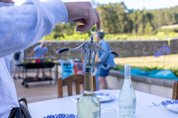 Waiter opening wine bottle with corkscrew during garden party