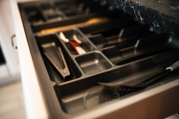 Modern kitchen drawer with organized spoons,forks and knives closeup. Kitchen space organization.