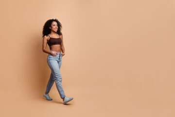 Young stylish woman enjoying casual attire in a modern beige background while expressing beauty and...