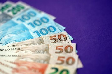 Close up of brazilian reais money bills in big amount on purple. Pile of Brazil real currency