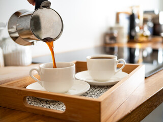 Pouring coffee from coffee pot into cups, close-up