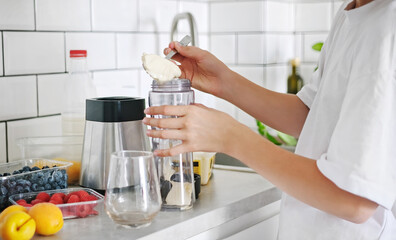 Little Girl Adding Ice Cream To A Milkshake In A Sport Shaker In The Kitchen
