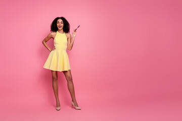 Young woman in a stylish yellow dress smiling joyfully against a vibrant pink background exuding charm and playfulness