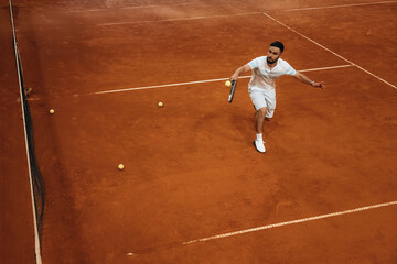 Top down view. Man is playing tennis indoors in the hangar