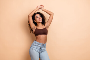 Young cheerful woman in casual outfit enjoys a relaxed moment against a beige background