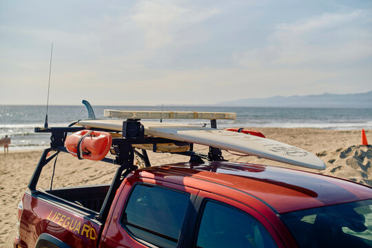 Lifeguard pickup truck with surfboards parked on a sunny beach by the ocean. Los Angeles, USA
