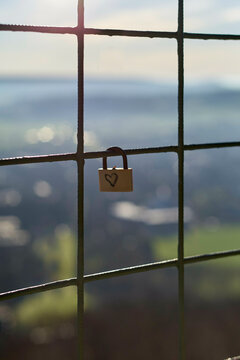 A heart-decorated padlock attached to a metal fence overlooking a scenic landscape. Weser Uplands, Germany