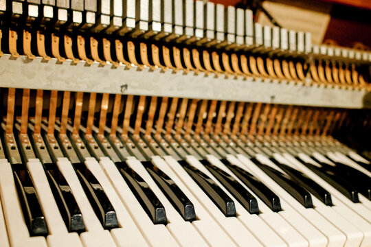 Close-up view of piano keys and the intricate hammers inside an upright piano.