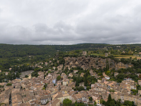 Aerial view of terracotta rooftops nestled amidst the verdant hills, ancient stone buildings rise against the moody sky, Cotignac, Provence-Alpes-C&Atilde;&acute;te d'Azur, France.