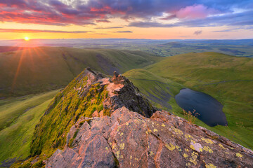 Spectacular summer sunrise overlooking Scales Tarn, seen from Sharp Edge on Blencathra in The Lake...