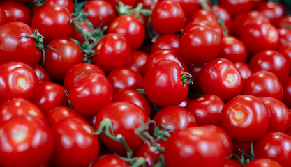 A macro, top-down view of a vibrant food background featuring a group of ripe, red cherry tomatoes clustered together in bold, natural color.