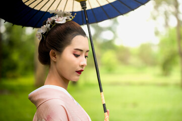 Beauty young Japanese woman dressing in traditional kimono or yukata holding umbrella walking in...