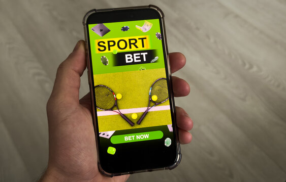 Man betting on sports, holding smart phone with working online betting mobile application - Powered by Adobe