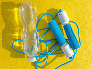 Jump rope and water bottle on sports mat, top view. Fitness and workout gear, healthy lifestyle...