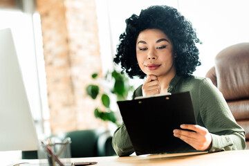 Professional businesswoman analyzing documents at the office while working on a corporate project...