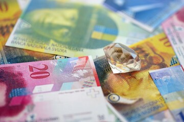 Swiss franc banknotes and diamond. The current francs money bills and gem lies on table