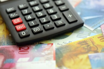 Swiss franc banknotes and calculator. The current francs money bills and calc lies on table