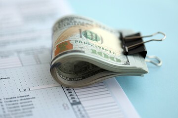 Big amount of United States hundred dollar bills in bunch on table with tax return form