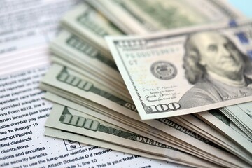 Big amount of United States dollar bills on table with tax return form close up