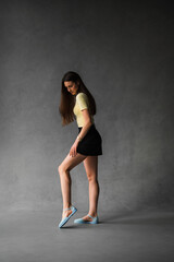 A woman in a yellow shirt and black shorts stands on one leg