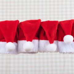 Row of festive red santa hats with white trim and pom poms hanging