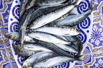 Fresh sardines lying on decorative plate, displaying culinary delights