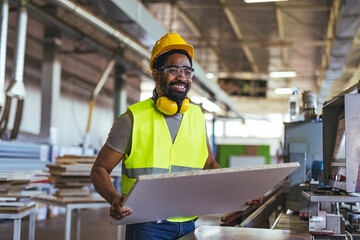 Smiling Worker Holding Panel in Manufacturing Plant