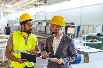 Industrial Engineers Collaborating in a Factory Setting with Safety Gear