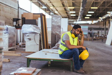 Tired Factory Worker Sitting on a Bench in an Industrial Setting