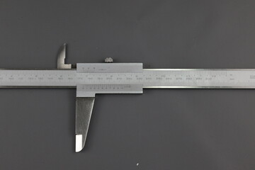 Metal vernier caliper, construction and working measuring tool, isolated on a grey background. Universal tool designed for high-precision measurements of external and internal dimensions. 