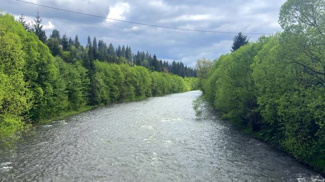mountain river, a strong rapid current in the middle of a mountainous flatter area, rainy weather, underwater stones, fresh water, a stream of water, a shallow reservoir