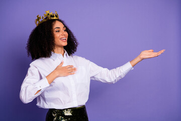 Confident young woman wearing a golden crown showing a hand gesture while smiling against a vibrant...