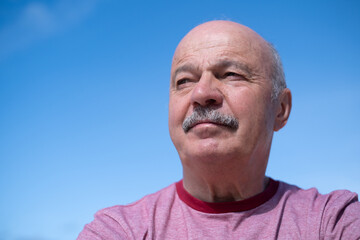 Elderly Spanish Man Against Blue Sky, Slightly Sad and Frowning