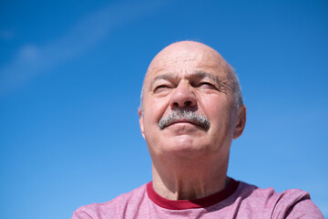 Elderly Spanish Man Against Blue Sky, Slightly Sad and Frowning