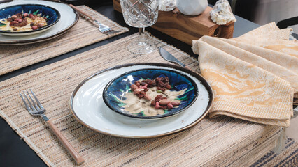Plate of food sits on a table with a napkin and a fork. napkin is yellow and has a design on it