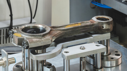 A connecting rod of a car engine piston undergoes maintenance on a repair stand.