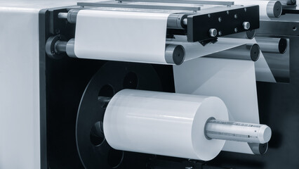 A machine with a roll of polyethylene plastic film on it.  machine is in a factory. industrial food...