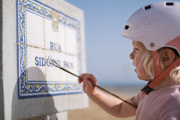 Little Girl in a Bike Helmet Learning to Read a Street Sign