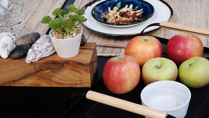 Table with a bowl of apples and a bowl of nuts. There are four apples and a potted plant