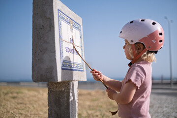 Little Girl in a Bike Helmet Learning to Read a Street Sign