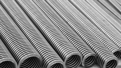 Row of stainless steel corrugated high pressure pipes in silver color. pipes are long and thin. Mechanical industrial concept background blue tone.