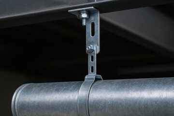 Metal air duct suspended by adjustable bracket in industrial setting highlighting engineering and industry applications