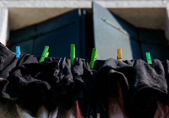 Colorful clothespins securing dark laundry on line outdoors