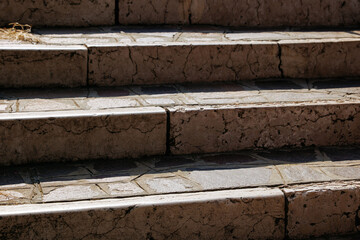 Weathered stone steps with cracks and sunlit shadows in outdoor urban setting