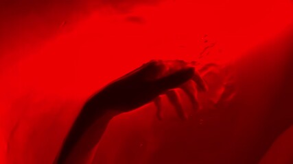 close-up of woman's hand under red water performs chaotic smooth movements water illumination bubbles in the air dance of hands twinkling lights neon light floating