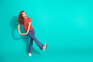 Young woman in a casual striped t-shirt posing against a bright turquoise background with dynamic...